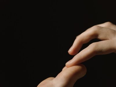 Close-up of a person's hands in a meditative gesture.